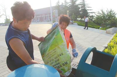 李新安帮母亲把垃圾倒入垃圾箱
