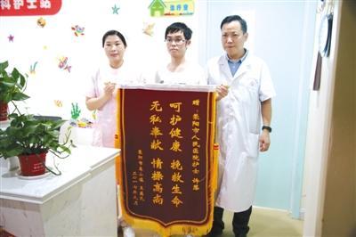 王振家的儿子（中）将锦旗送到许慧（左）和荥阳市人民医院副院长李广明（右）手中