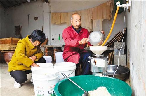 王庄村脱贫户王万才(右)依托“到户增收”项目开起了豆腐坊,踏上稳定增收路。 (资料图片)