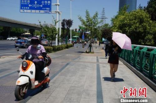 高温下，郑州市民做好防晒措施出行。　韩章云　摄