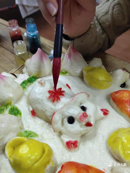 给蒸熟的花馍涂上可食用的颜料。