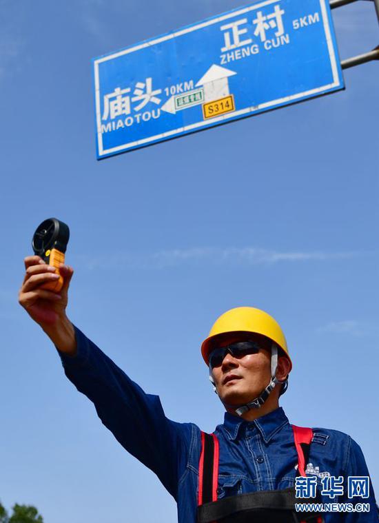 7月30日,在河南省新安县正村镇上坡村,尤宁在带电作业现场测量风速。