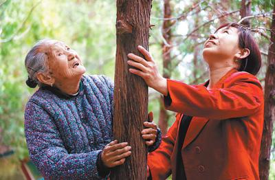 （靳月英带孙女一起察看当年种下的侧柏。霍亚平摄 人民视觉）