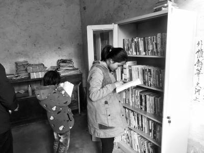 爱心人士送来的新书架里装满图书，小姐妹拿着各类书籍爱不释手。