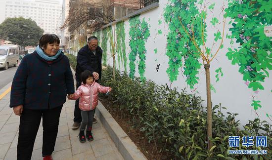 2月25日，郑州市金水区政一街，家长带着孩子在欣赏“装扮”一新的文化墙。