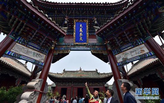在开封山陕甘会馆内，许世杰为在场游客讲解牌楼历史(4月26日摄)。