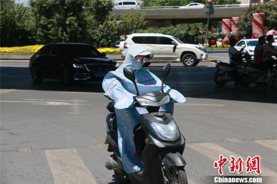 高温下，郑州市民做好防晒措施出行。　李超庆 摄