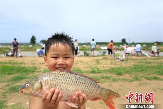 成功摸到大鲤鱼让小朋友开心不已　徐志清　摄