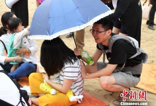 资料图:2017年5月,近200福州辣妈进行街头哺乳快闪活动,图为活动中一位丈夫帮妻子撑伞。 吕明 摄
