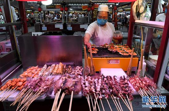6月2日，在河南省开封市鼓楼夜市，一名摊主在烤生蚝。