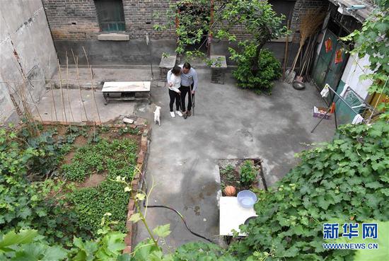 5月30日，韩红晓帮助丈夫贾洪涛在院子里行走锻炼。 新华社记者 李安 摄