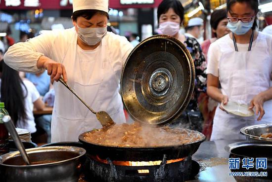 6月2日,在河南省开封市鼓楼夜市,一名小吃摊主在制作传统小吃炒凉粉。