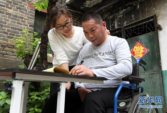 5月30日，韩红晓看着丈夫贾洪涛进行写字练习。 新华社记者 李安 摄