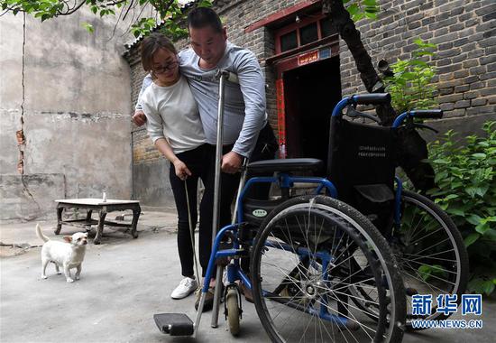 5月30日，韩红晓将丈夫贾洪涛扶上轮椅。 新华社记者 李安 摄