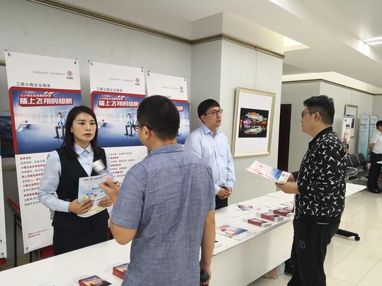 工行郑州分行工作人员在人民银行举办的政银企项目对接会上,向带贫企业、小微企业代表答疑解惑。