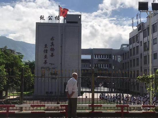 95岁的温江站在一所学校外。澎湃新闻记者 何利权 图