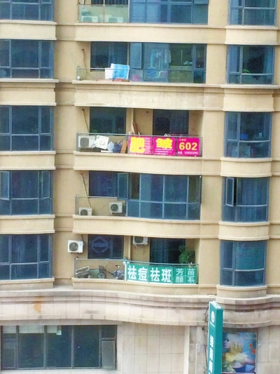 涉事美容店所在的小區樓上，掛著各類美容整形廣告。