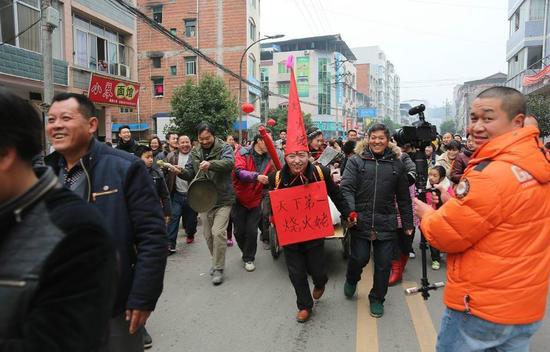 由公公頭戴尖尖帽，胸掛“天下第一燒火佬”牌子，用板車迎接兒媳婦新娘。