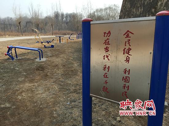 公园内的健身器材立在泥地里，空无一人。