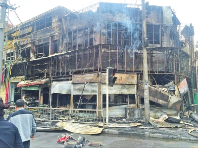 几家商户的店铺被烧后，剩下水泥框架和楼外的装饰钢筋。