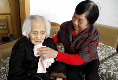 70岁的李秀芝在为113岁的婆婆张留擦洗。