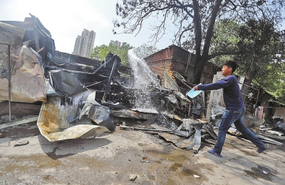 洗車行的工人用水潑灑殘余的火苗