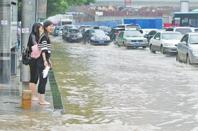 6月5日，郑州经三路，两个女孩儿在道牙上脱了鞋袜，准备过马路。