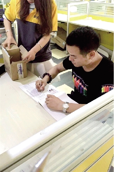 寄件人正在登记身份证,快递人员验视所寄物品