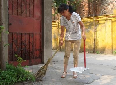 谭好芳在清扫地上的烟头、纸屑和落叶。