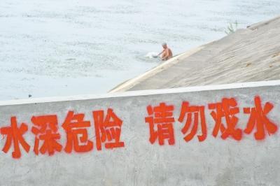 男子大白天在河边警示牌旁裸洗 称没钱去澡堂