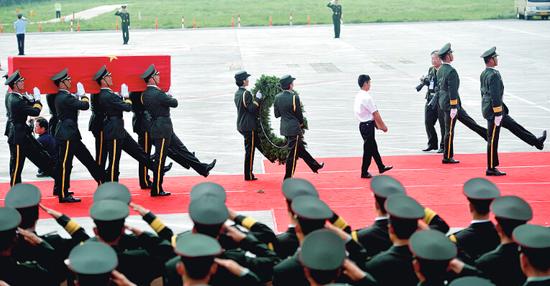 覆盖着中华人民共和国国旗的两位烈士李磊、杨树朋的灵柩被抬下飞机 