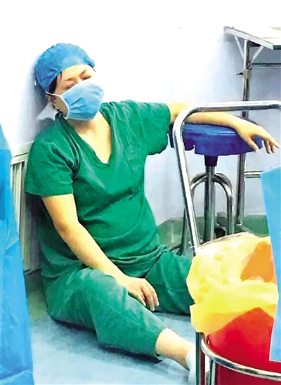  孕妇分娩后，古琳靠着手术室墙壁瘫坐在地上休息。