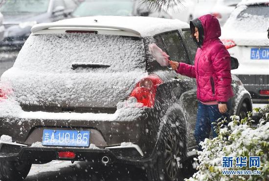 10月30日，一名长春市民在清扫汽车上的积雪。