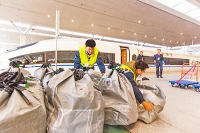 11月11日，在鄭州東發往哈爾濱西的G1264次高鐵列車站臺上，工作人員正在搬送快遞包裹。本報記者聶冬晗攝