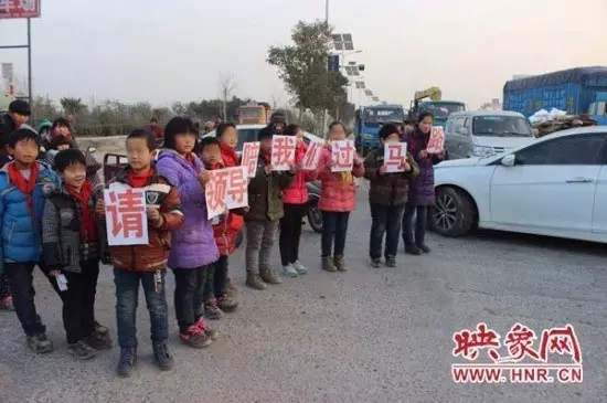 牌子上显示着“请领导陪我们过马路”的语句