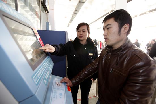 工作人员帮助旅客使用自动取票机