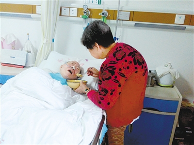 80岁的王书清正在喂瘫痪在床的老伴吃饭