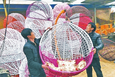 時(shí)尚的搖籃成為城里人青睞的家居用品，付云飛（右）和村干部一起展示搖籃成品。
