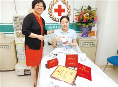 张晓丽手拿她捐献的造血干细胞很开心,与上海接受方代表吴颖菊合影