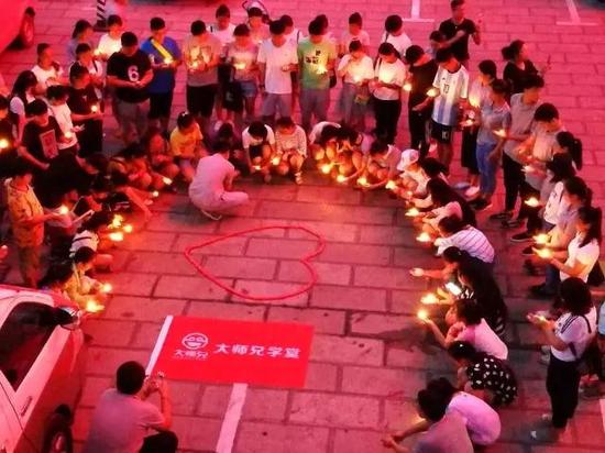 图二：师生们点燃红色爱心蜡烛祈祷，代表着“风雨同舟，我们同在”的美好愿景