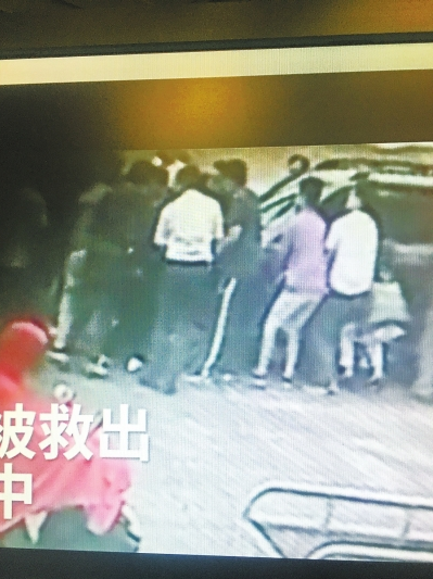 记者翻拍大伙合力抬车救人的视频画面
