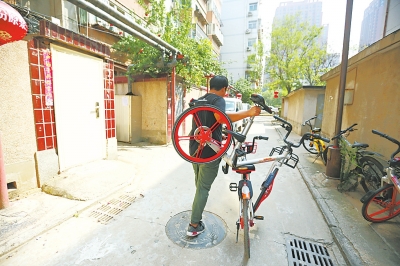 有些共享单车由于太阳能板被杂物遮挡,单车运营专员无法开锁,只能摞起来推着走。