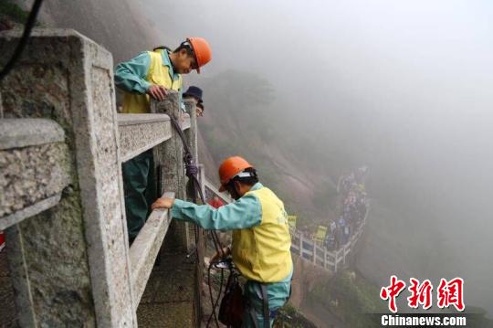 放绳工在同事的配合下完成下悬崖工作　汪钰　摄