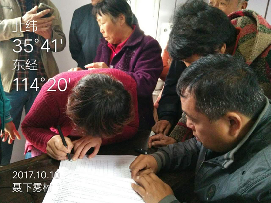 钜桥镇聂下雾村,投保农户核对自己身份信息、地块面积,并在投保明细表上签字确认