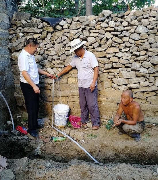 杨刚（左）查看贫困户蒋合顺家安装的自来水管道通水情况