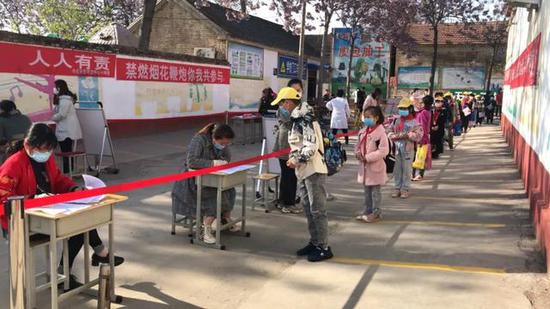  南乐县寺庄乡东寺庄中心小学学生在排队检测体温后入校