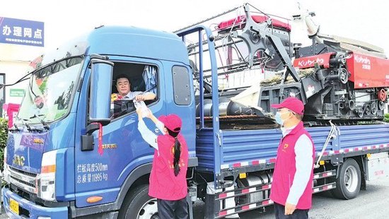 构林收费站工作人员向跨区机收司机发放矿泉水