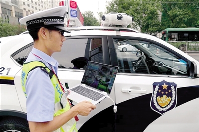 民警手持平板电脑能实时监控抓拍到的交通违法场景