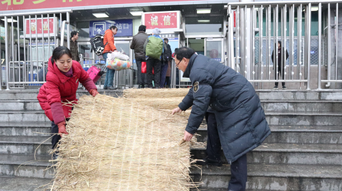 新乡车务段新乡站组织职工在站内平交道口铺设草垫、清理积雪，确保旅客出行安全。（赵婧摄）