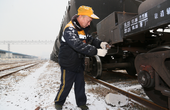 新乡车务段新乡站北运转车间职工在雪中检查危险品罐车状态。（王振兴摄）